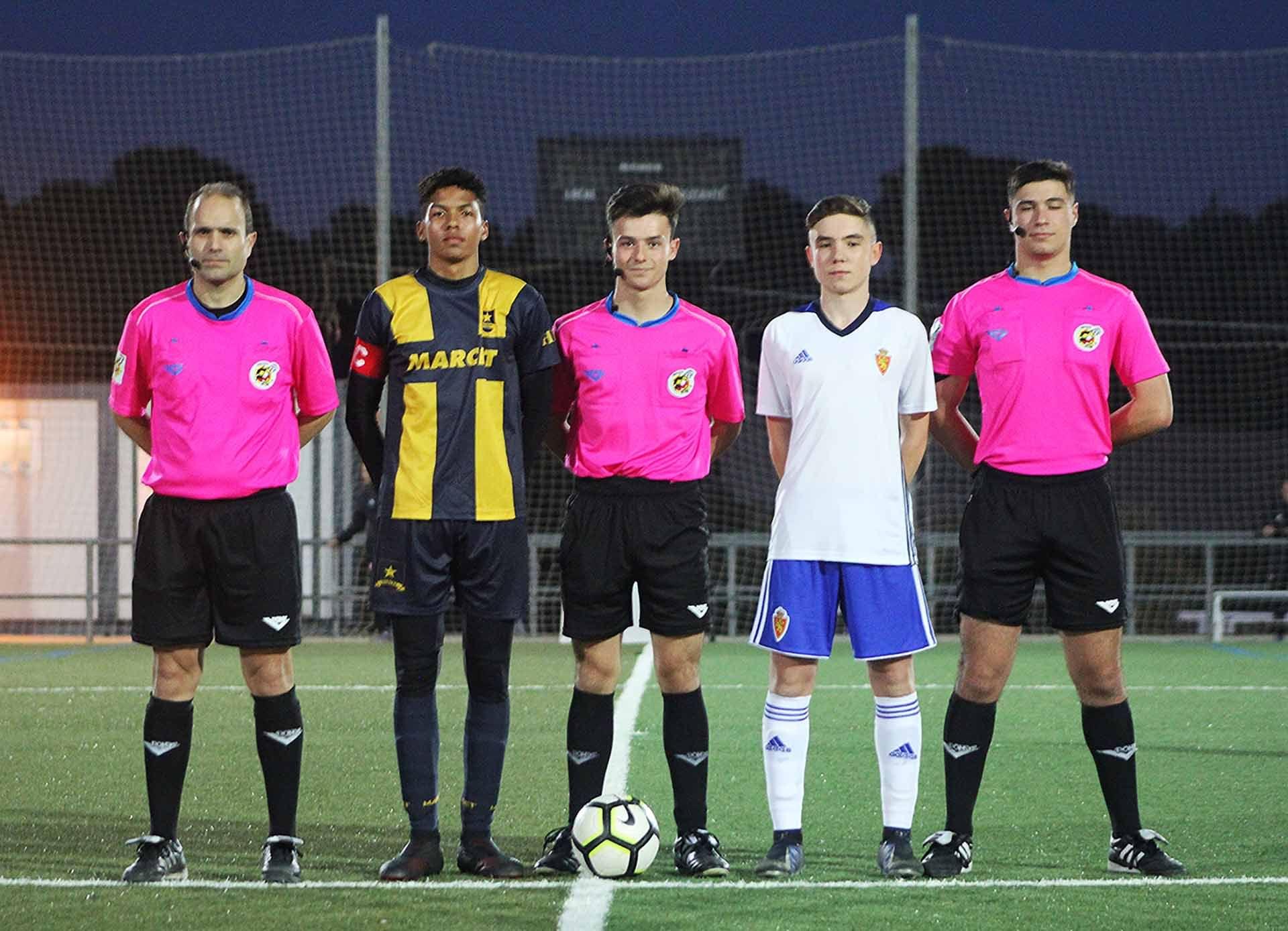 Marcet Football Academy captain stands alongside rival captain and referees before a game.